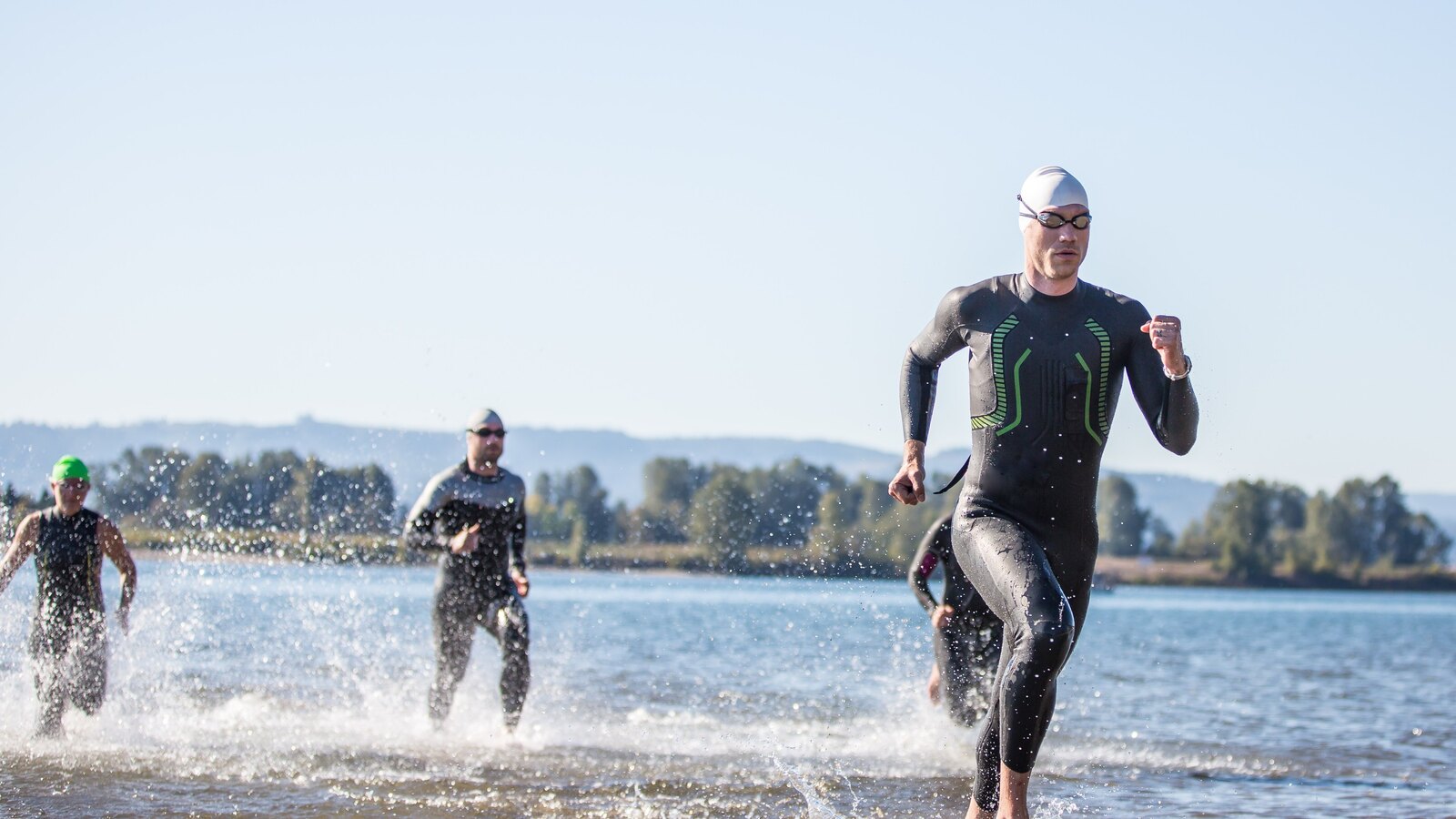Triathletes running out of the water towards transition