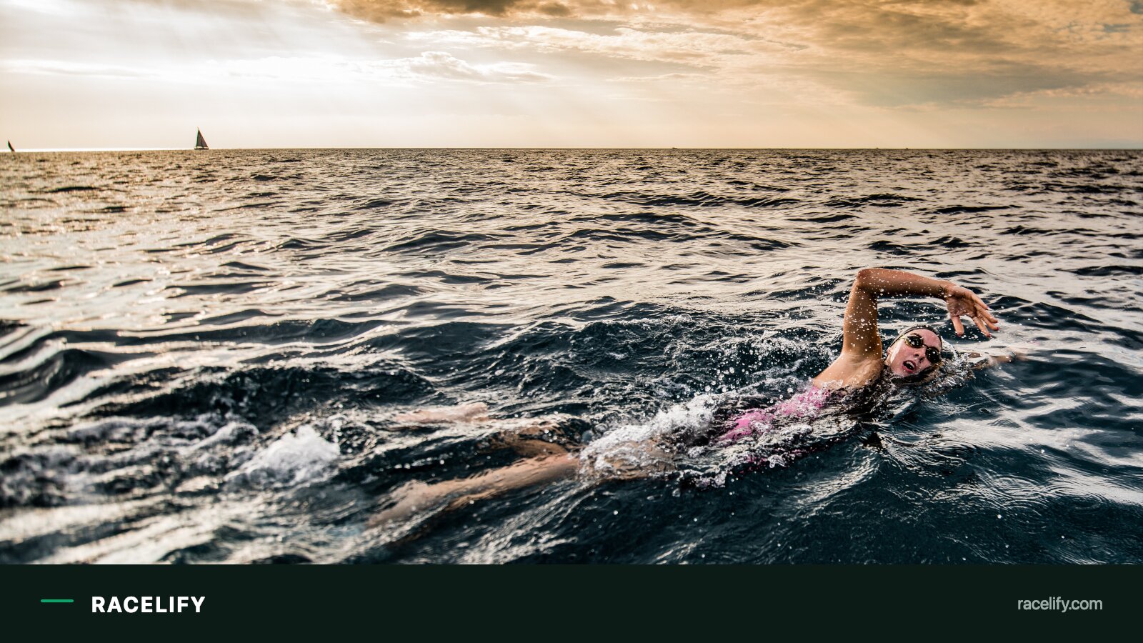 A triathlete swimming in open water with a compact inflatable safety buoy clipped to a waist belt, trailing behind on the surface.